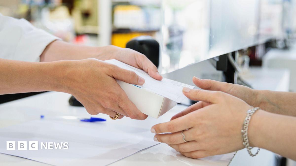 A pharmacist hands a box to a woman in a chemist's shop