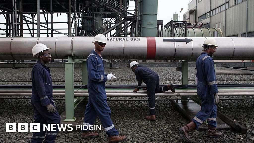 Gas workers dress for protective gear waka past large pipeline labelled 'natural gas'