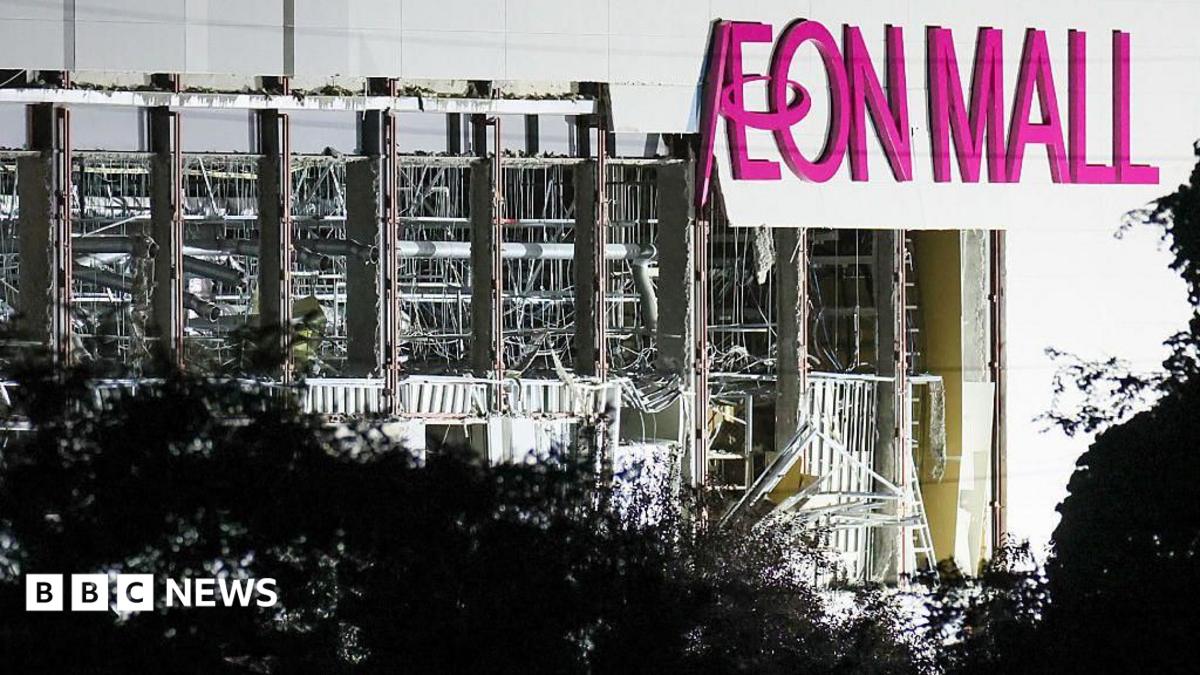 A collapsed shopping mall with a pink sign Aeon Mall on its side