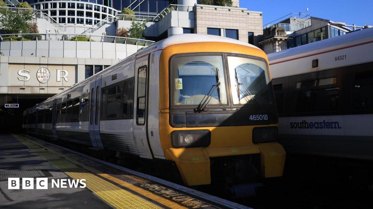 Two Southeastern trains stopped at platforms at Charing Cross station. The station building is in the background with the