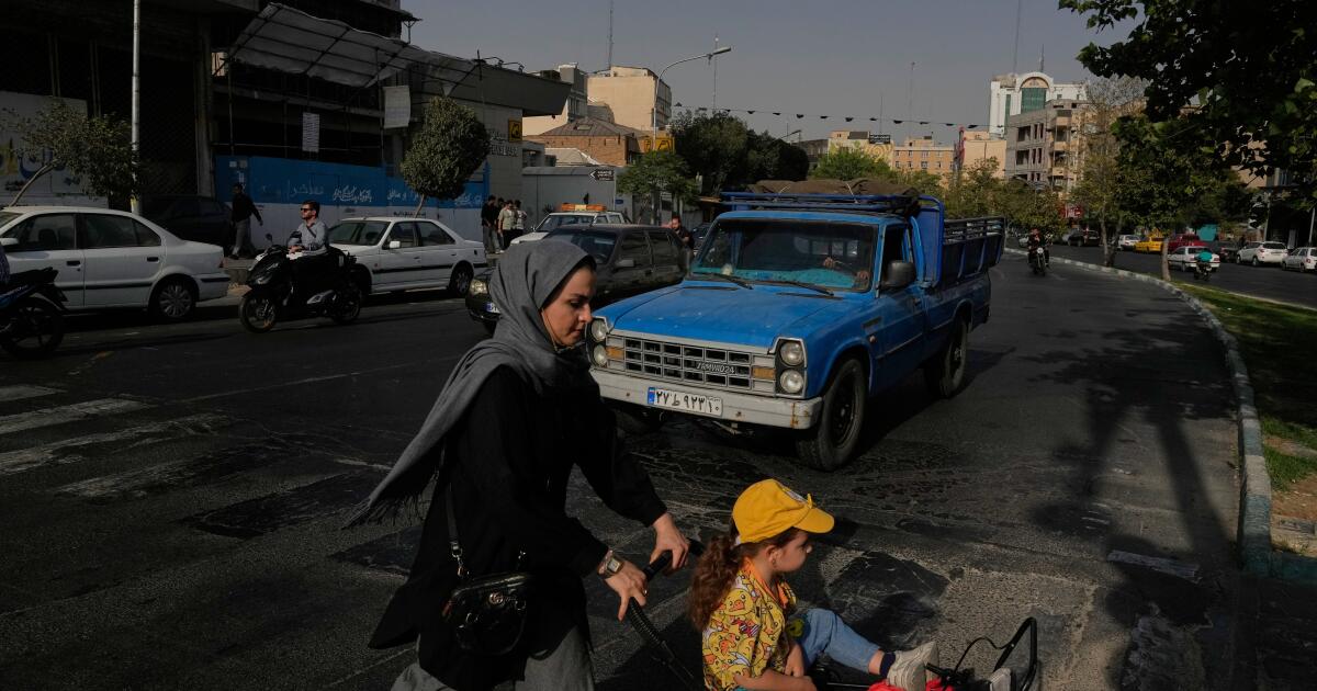 A woman crosses a street with a girl in downtown Tehran, Iran, Wednesday, July 22, 2026. (AP Photo/Vahid Salemi)