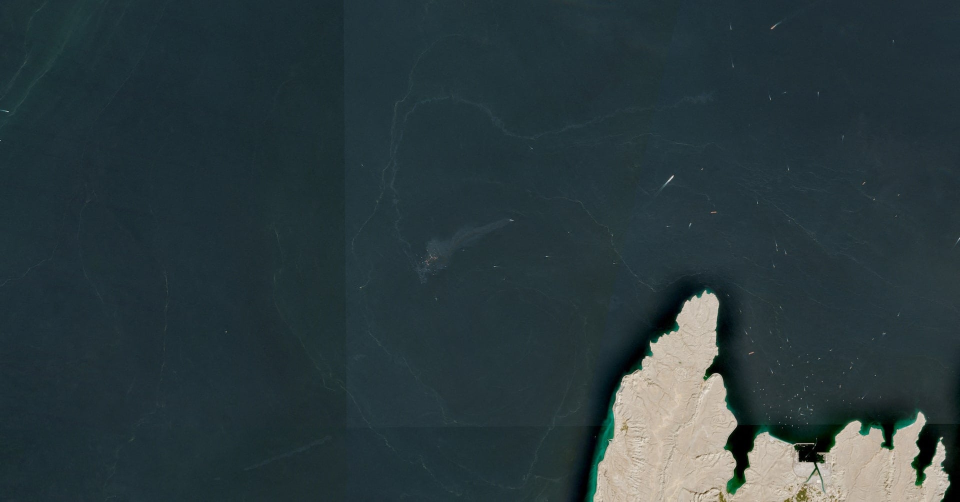 A satellite image shows containers and items floating in the water after a vessel sank near the Strait of Hormuz, off the